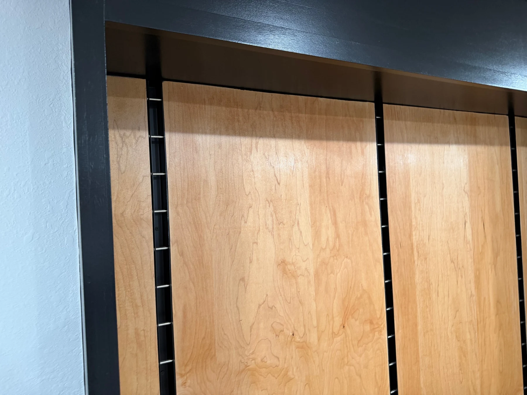 Finished maple panel faces beside the exposed slot of a recessed steel display standard