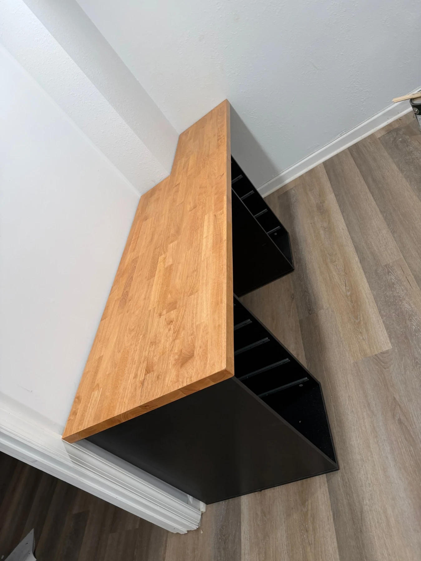 Overhead view of a fitted wood countertop with a notch at the wall and an angled end above a black base