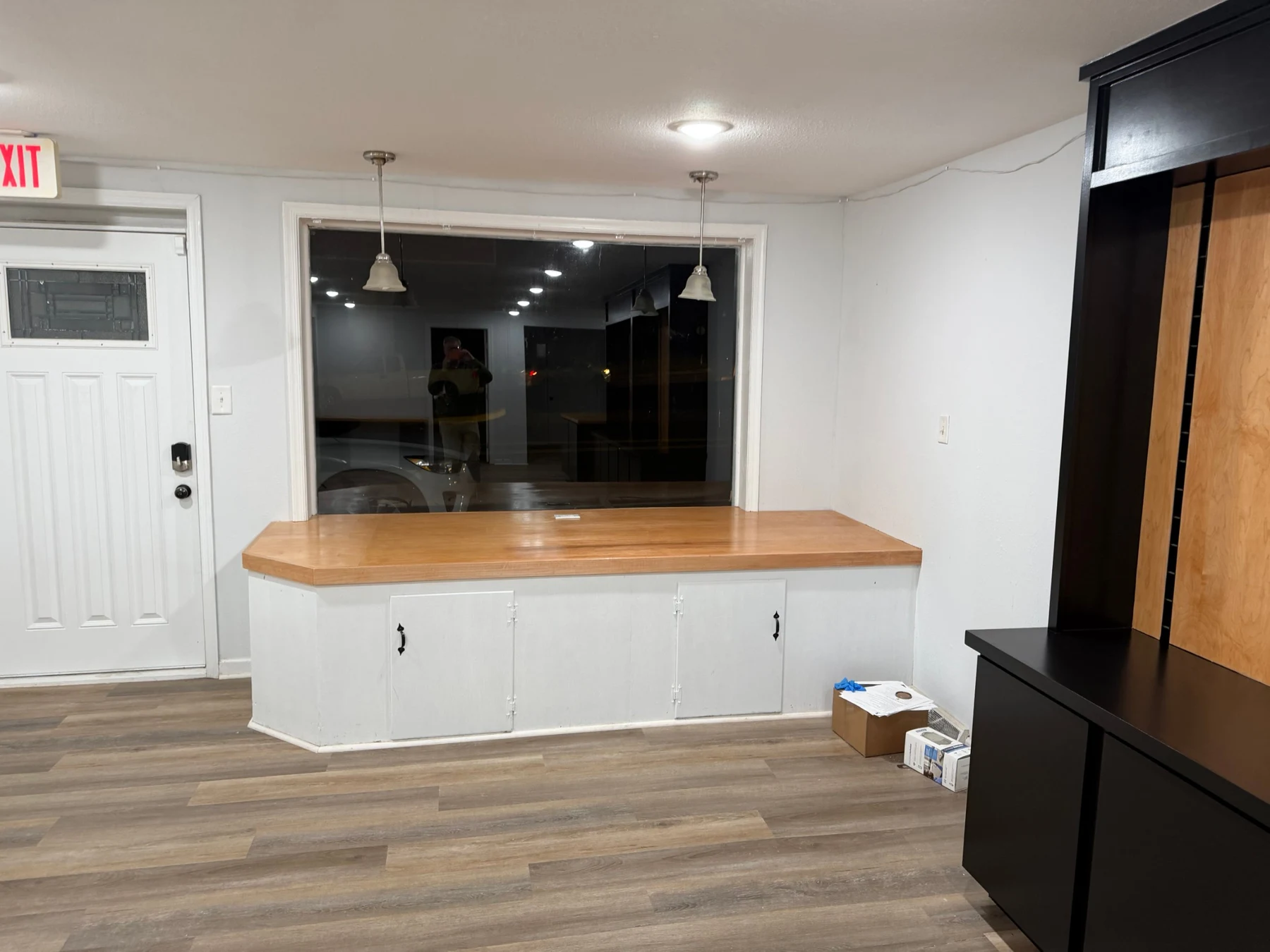 Finished wood-topped window bench above the original white base with access doors, beside the studio entrance